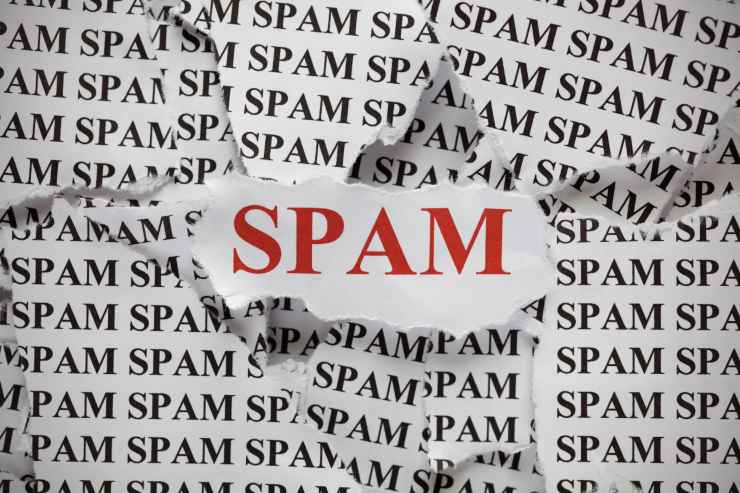 Scritta "spam" rossa su foglio di carta ritagliato, sopra ad altri foglietti con scritto "spam"