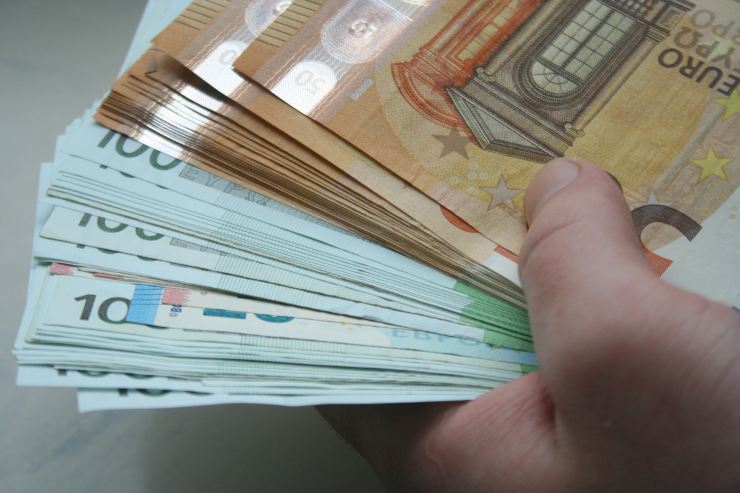 Uomo che tiene in mano tante banconote euro