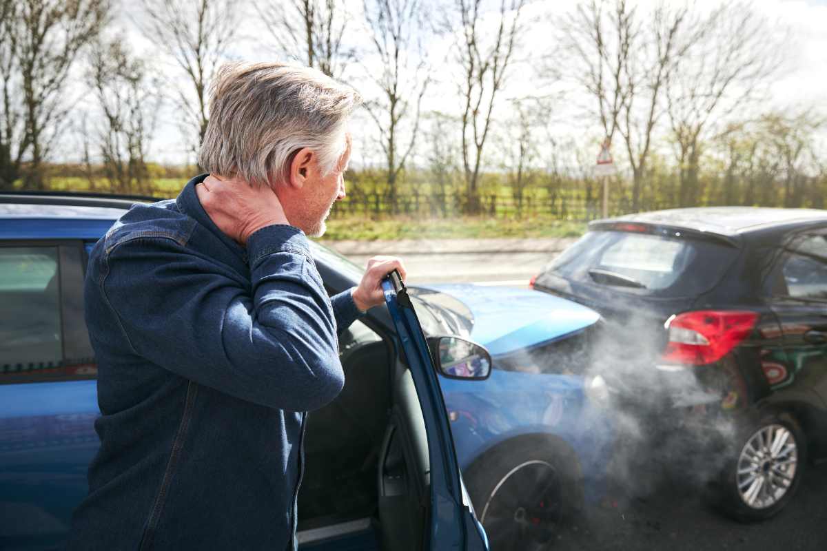 Uomo preoccupato dopo un'incidente tra la sua e un'altra auto