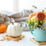 Composizione di fiori in tazza di fianco a zucche