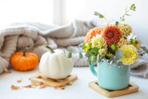 Composizione di fiori in tazza di fianco a zucche