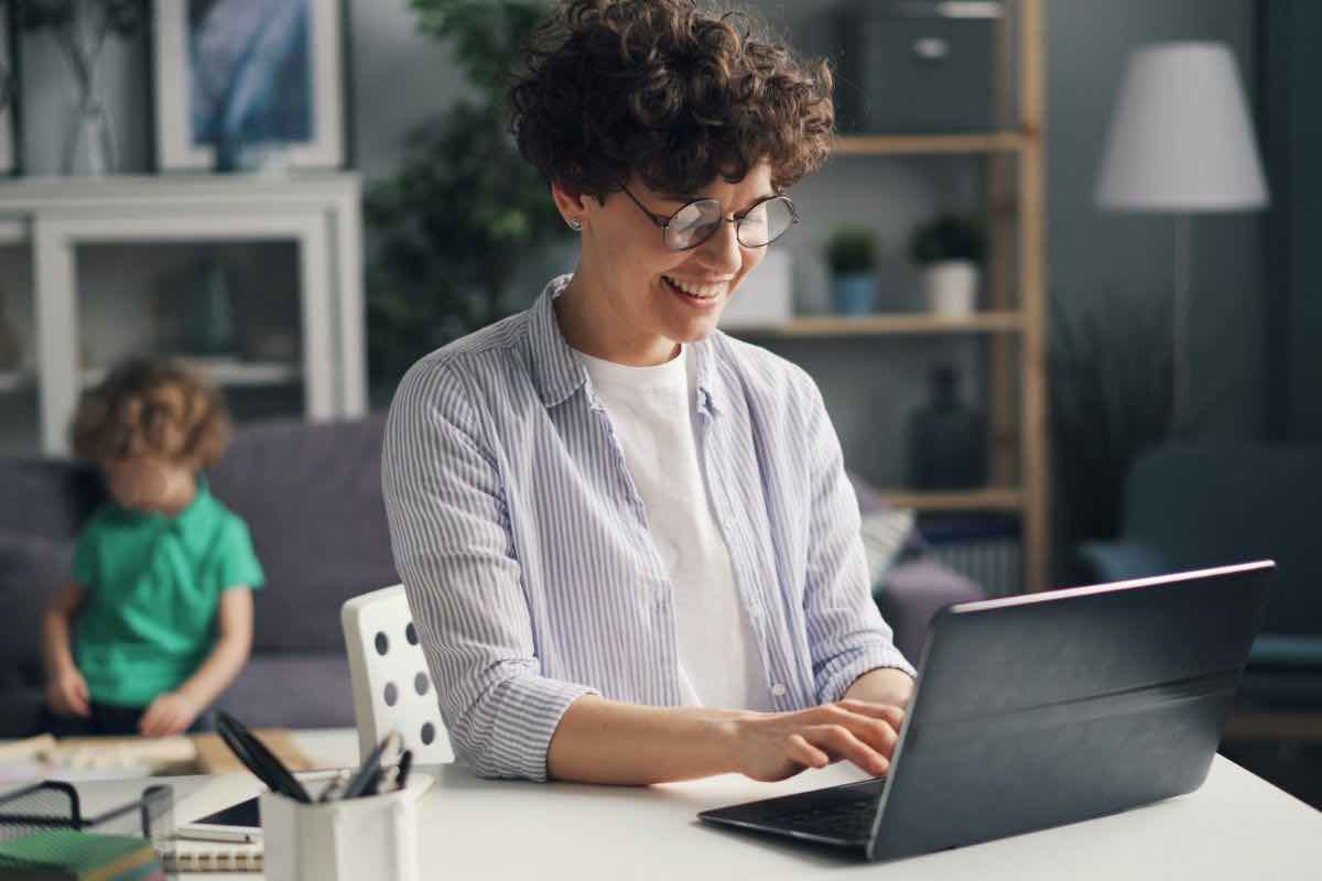 Donna che lavora al pc e bambino in secondo piano