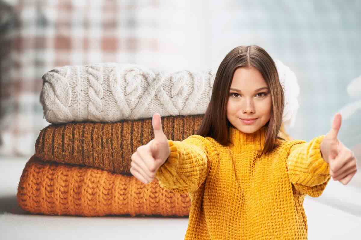 Ragazza pollici in su, dietro di lei maglioni