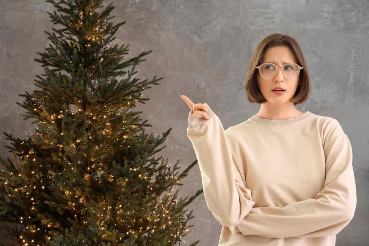 Donna indica albero di Natale con lucine