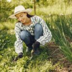 Donna inginocchiata a terra che cura l'orto